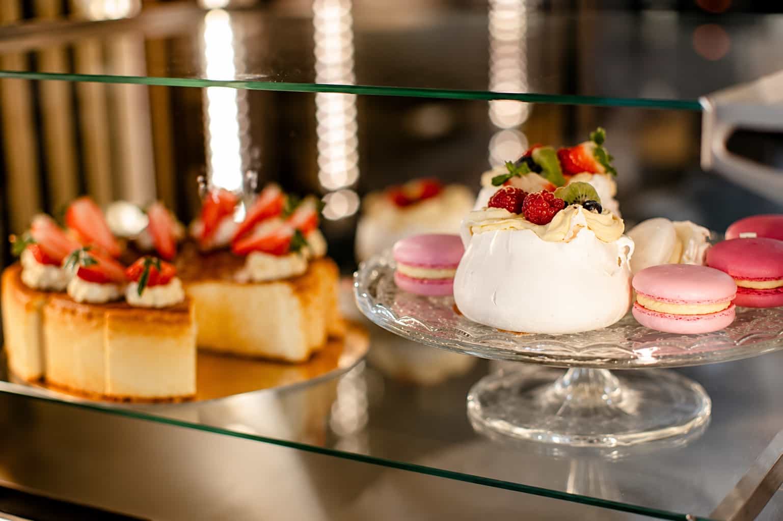 Witryna pełna domowych deserów — beza Pavlova, sernik z truskawkami i makaroniki — kawiarnia Kawałek Zielonka